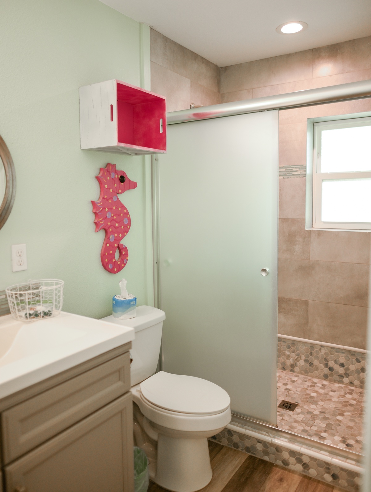 Your private bathroom features a spacious walk-in shower with beautiful tile work and playful coastal decor to brighten your morning routine.