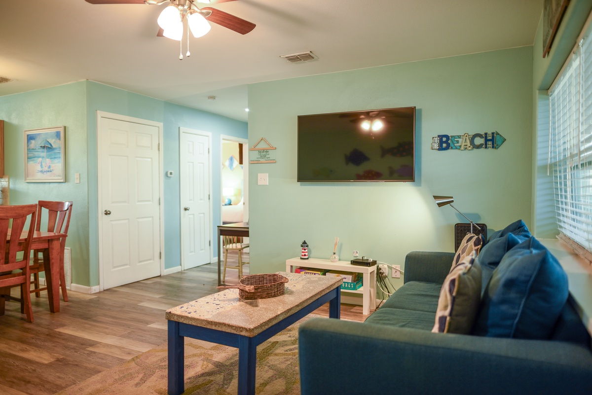 Relax in your coastal-themed living room with soft aqua walls, cozy seating, and beach decor that makes you feel instantly at home.