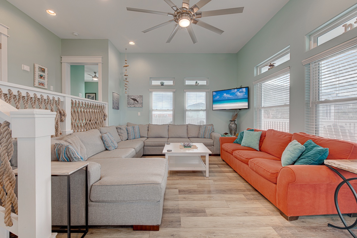 Sink into plush sectional seating while ocean breezes from your ceiling fan keep you cool in this bright coastal living room.