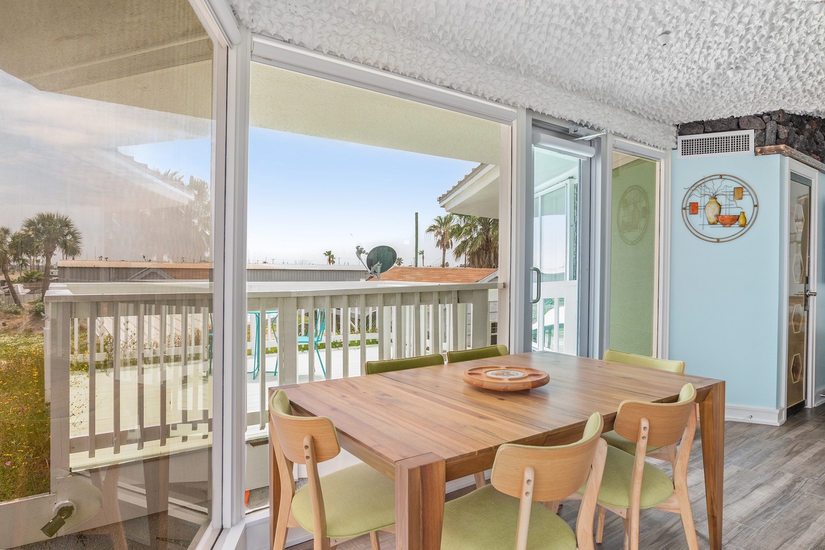 Your bright dining space opens to a sunny balcony with tropical palm views, creating the perfect spot for morning coffee or evening meals.