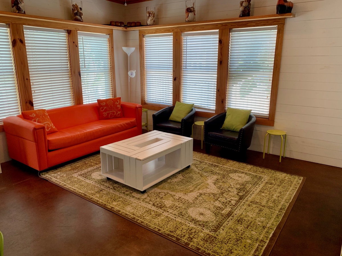 Settle into your bright corner living room where vibrant orange and deep leather seating create the perfect retreat.