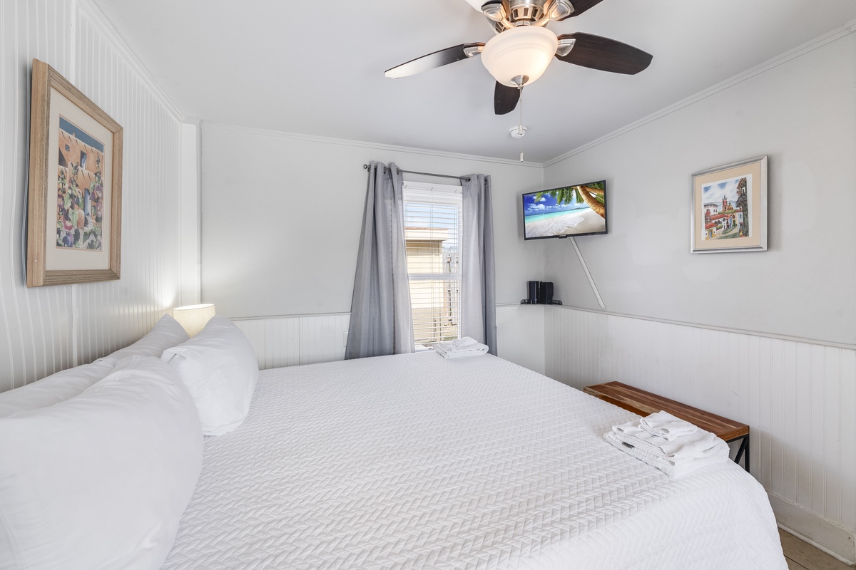Unwind in your peaceful bedroom with crisp linens, ceiling fan, and wall-mounted TV for cozy movie nights.