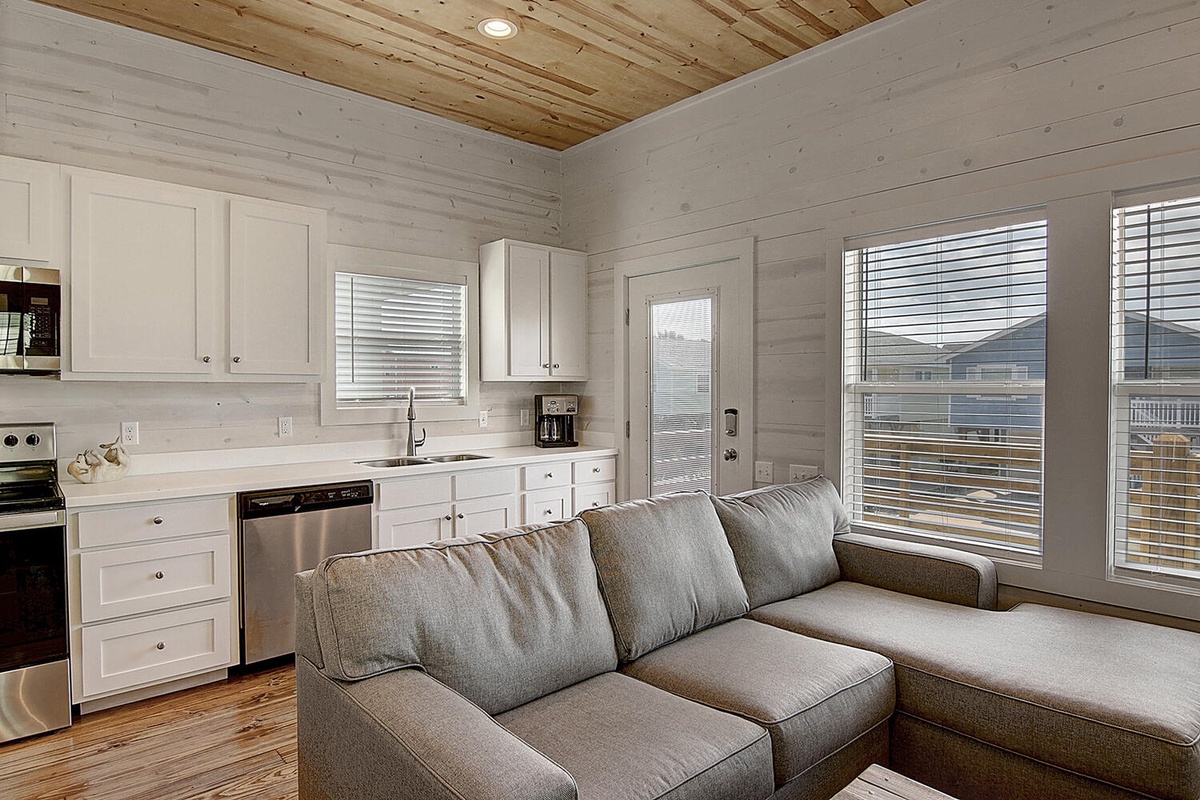 Unwind in your stylish open-plan living space where rustic wood meets modern comfort. The sectional sofa invites relaxation while you enjoy the bright kitchen.