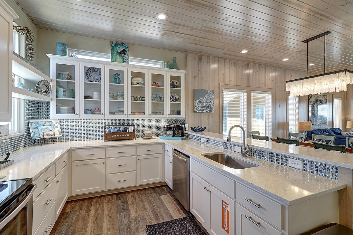 Your coastal-inspired kitchen invites culinary adventures with sparkling white counters, ocean-blue backsplash, and dining space.