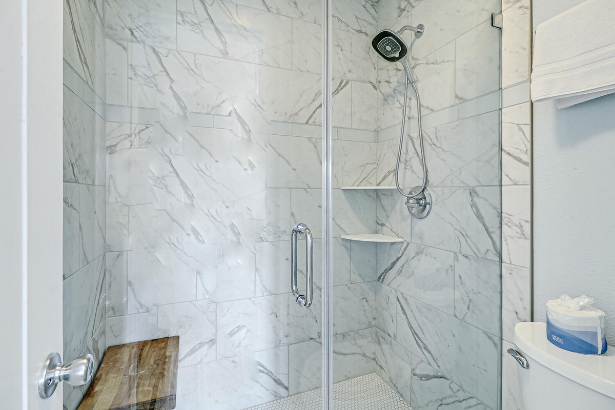 Step into your luxurious marble-wrapped shower with rainfall head and built-in shelves for pure spa-like indulgence.