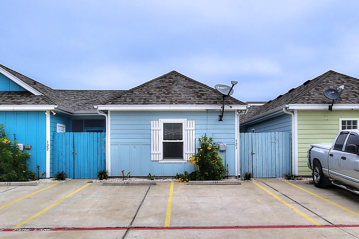 Colorful beachside cottages with designated parking spaces create a charming coastal village atmosphere.