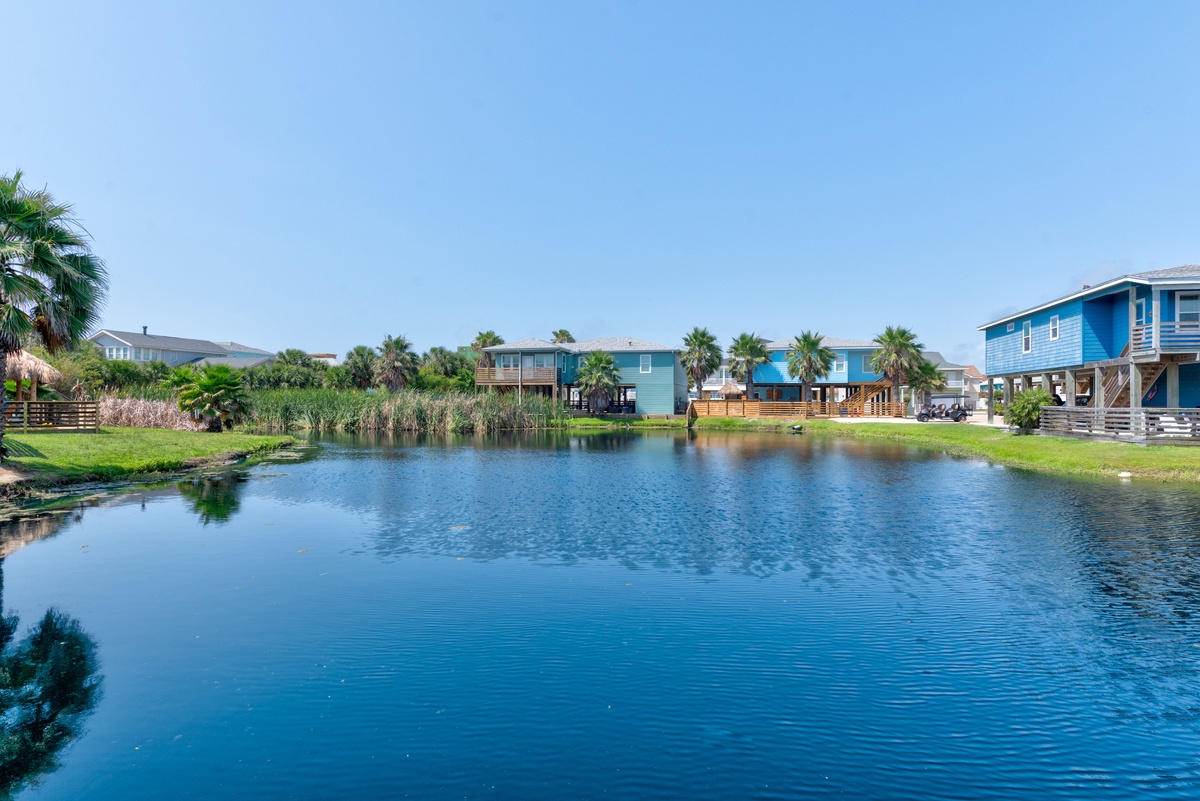 Peaceful waterfront community featuring colorful beach homes surrounded by palm trees and pristine canal waters under clear blue skies.
