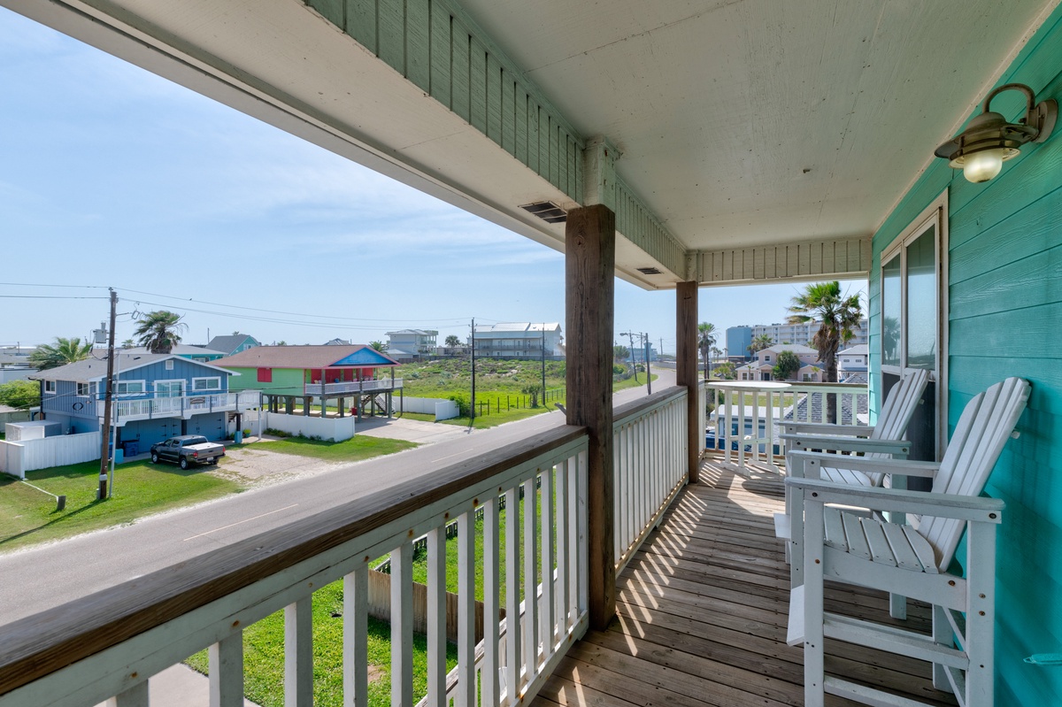Relax in white Adirondack chairs on your covered 2nd floor balcony, watching neighborhood life unfold below while enjoying coastal breezes and colorful beachside views.