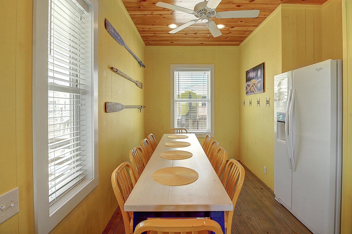 Gather your group around this spacious dining table with nautical charm, where wooden paddles and warm yellow walls create a cozy coastal atmosphere.