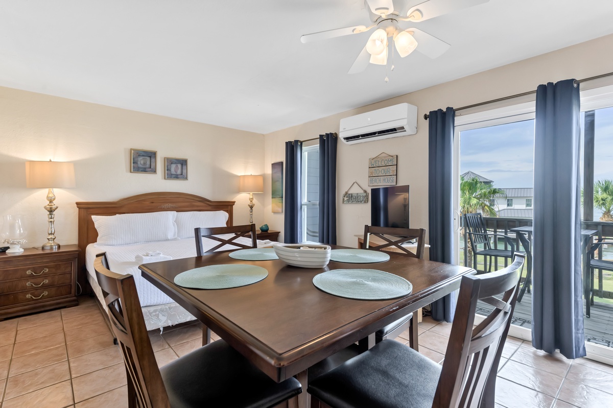 Your comfortable retreat features a cozy bedroom with dining space, ceiling fan, AC, and balcony access for relaxing moments.