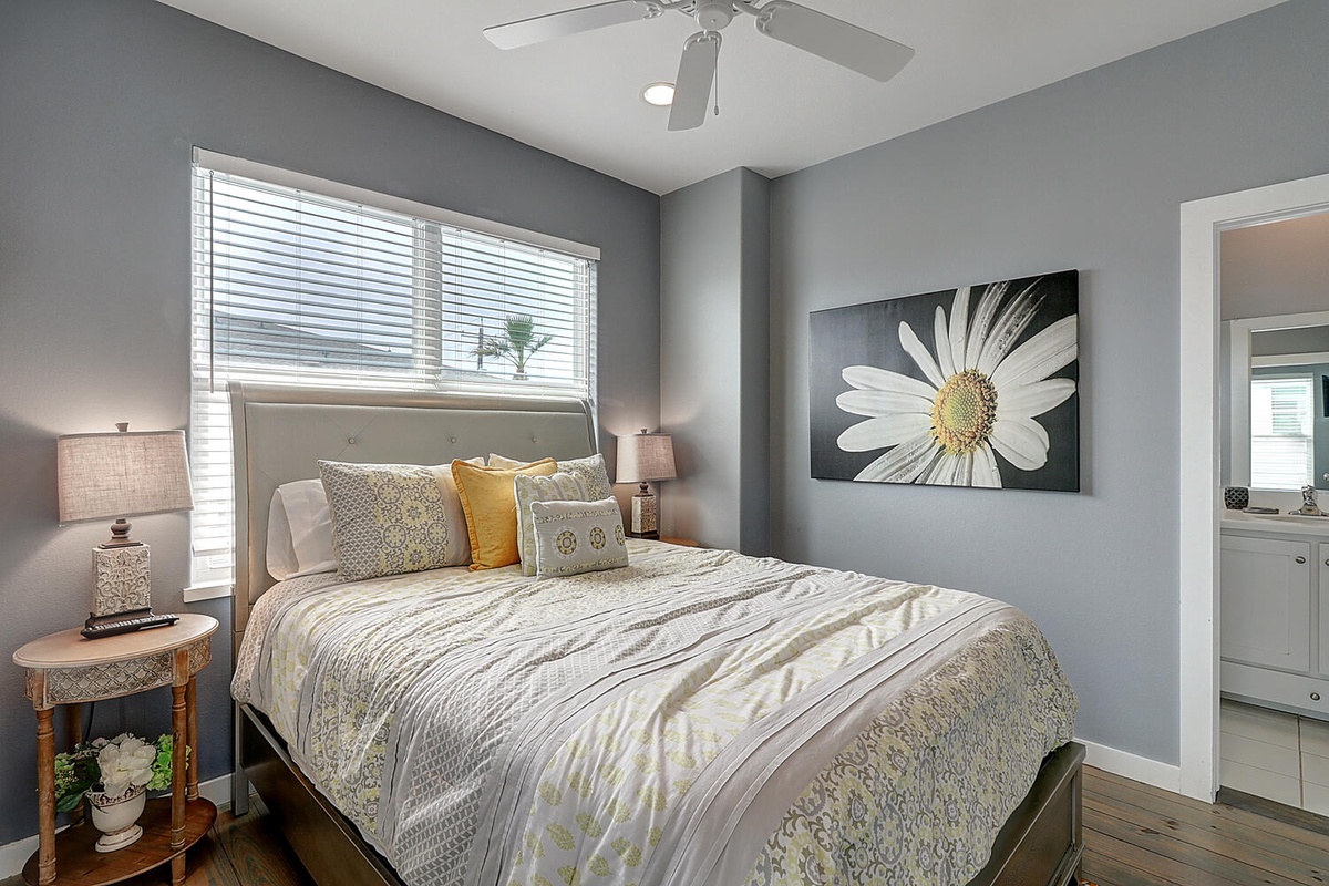 Drift off in this serene bedroom where soft gray walls and cheerful artwork create your perfect retreat.