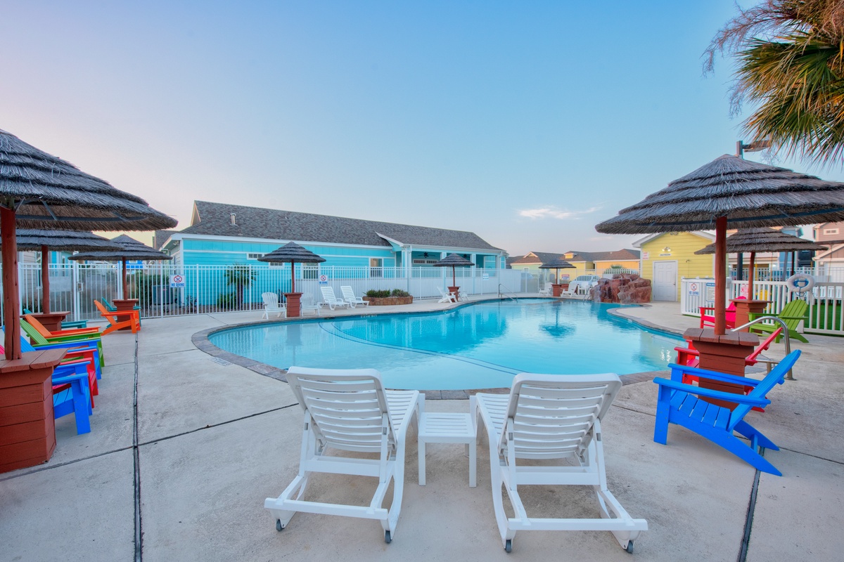 Dive into relaxation at your tropical pool oasis, surrounded by vibrant loungers and swaying palms under endless blue skies.