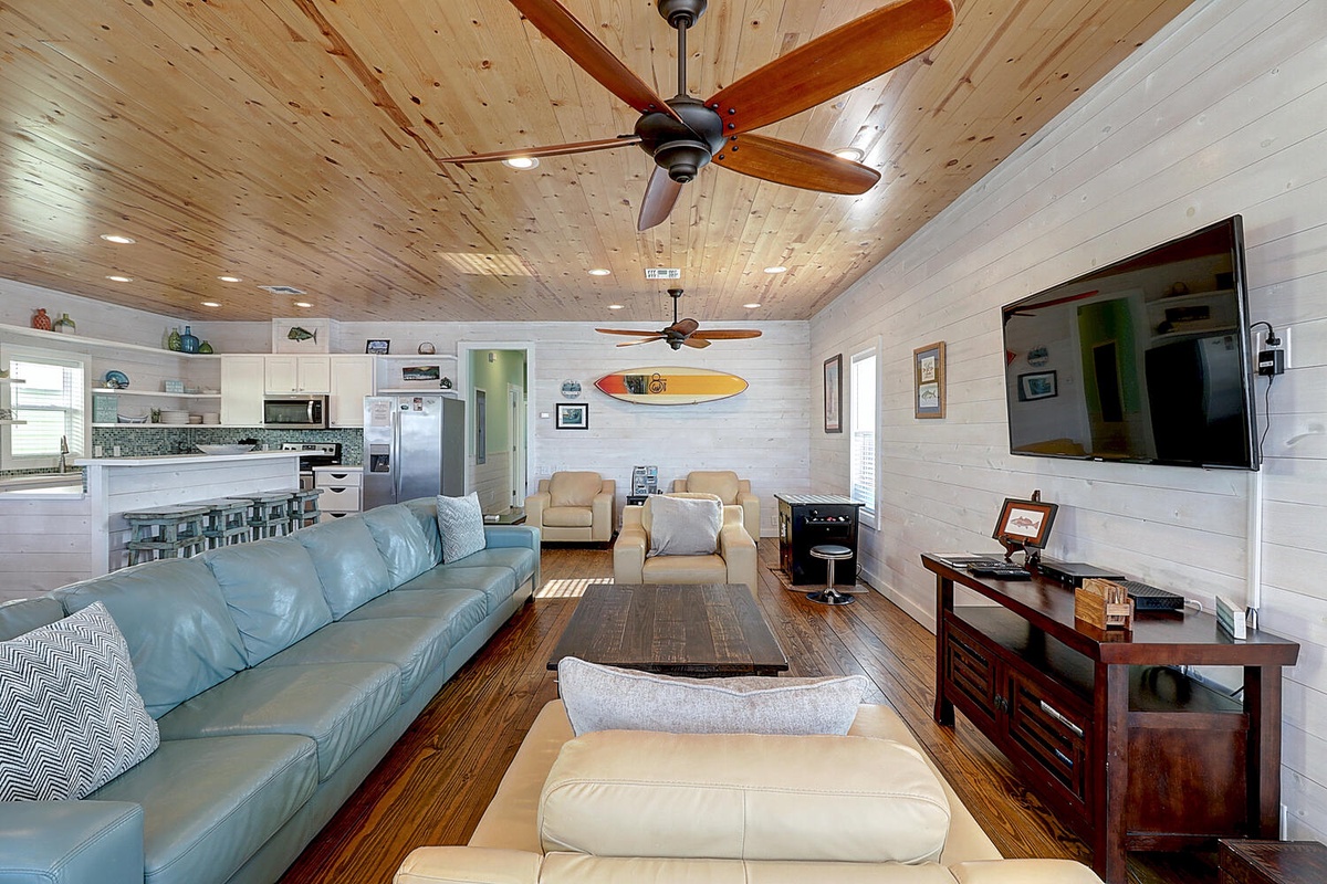 Relax in your bright, coastal-inspired living space with comfortable seating, full kitchen, and surfboard décor creating the perfect beach house vibe.