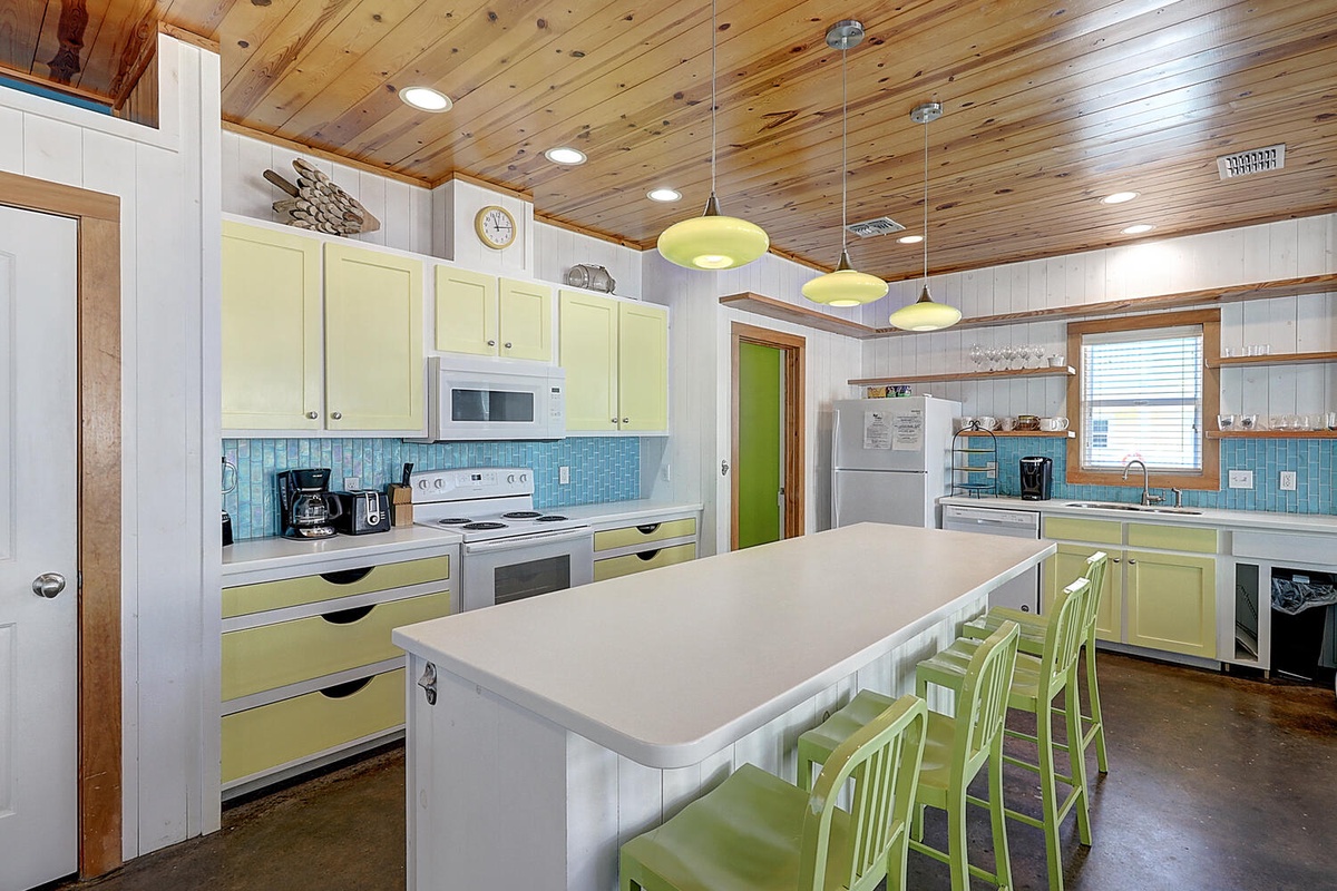Your bright, fully-equipped kitchen awaits with cheerful green cabinets, spacious island seating, and everything needed for memorable meals together.