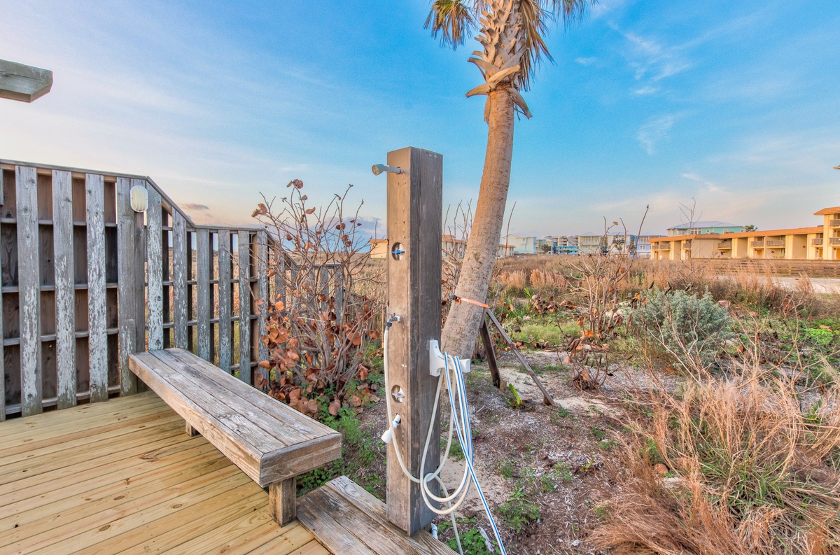 Wooden deck with bench overlooking natural dunes and palm trees, creating a peaceful coastal retreat setting.