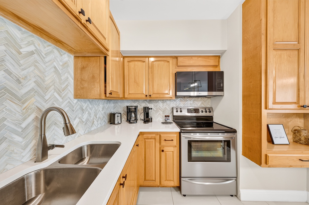 Your fully equipped kitchen features stainless steel appliances, elegant herringbone tile backsplash, and generous counter space for preparing meals during your stay.