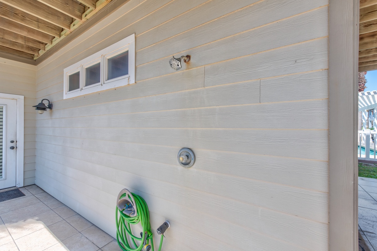 Convenient outdoor shower area with garden hose for rinsing off after beach days or outdoor adventures.