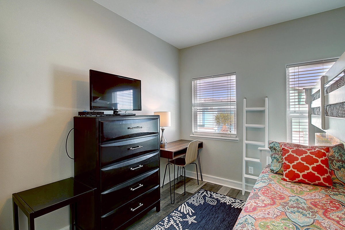 Your bright bedroom features a flat-screen TV, spacious dresser, and cozy work desk by the window.