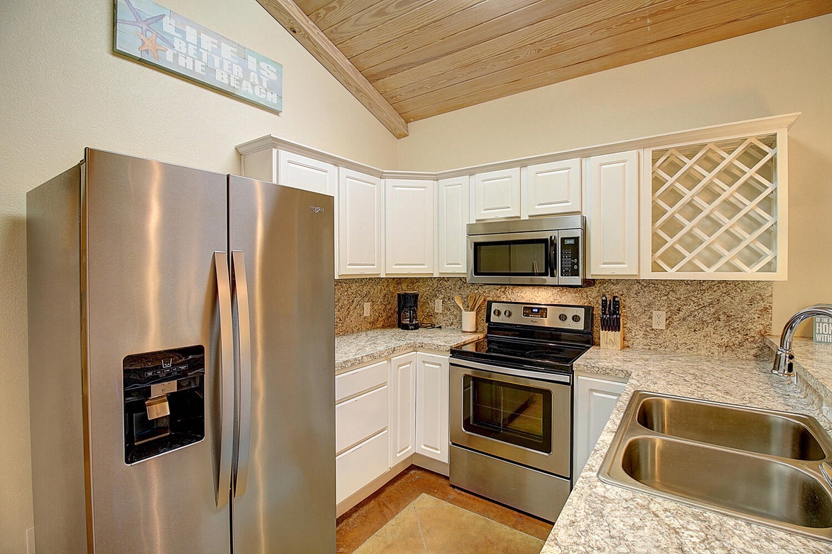 Your fully equipped kitchen features granite countertops, stainless steel appliances, and warm wooden ceiling beams.