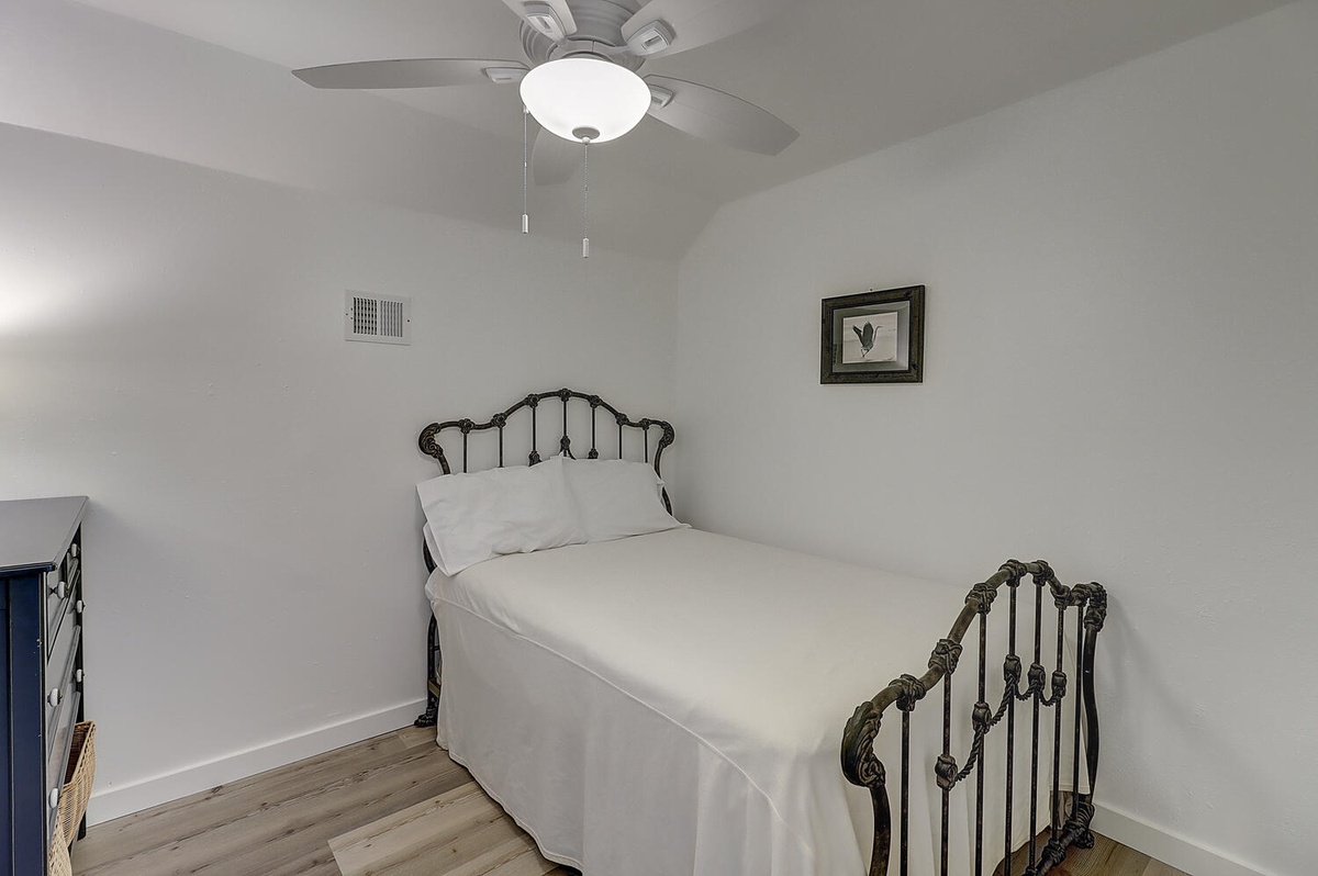 Rest peacefully in your charming bedroom with crisp white linens and elegant vintage iron bed frame.