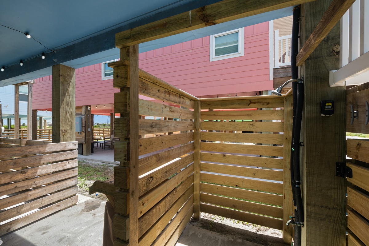 This charming pink cottage features natural wood accents and a covered outdoor space, creating a welcoming coastal retreat. The property's distinctive character and thoughtful design offer a relaxed beachside atmosphere.