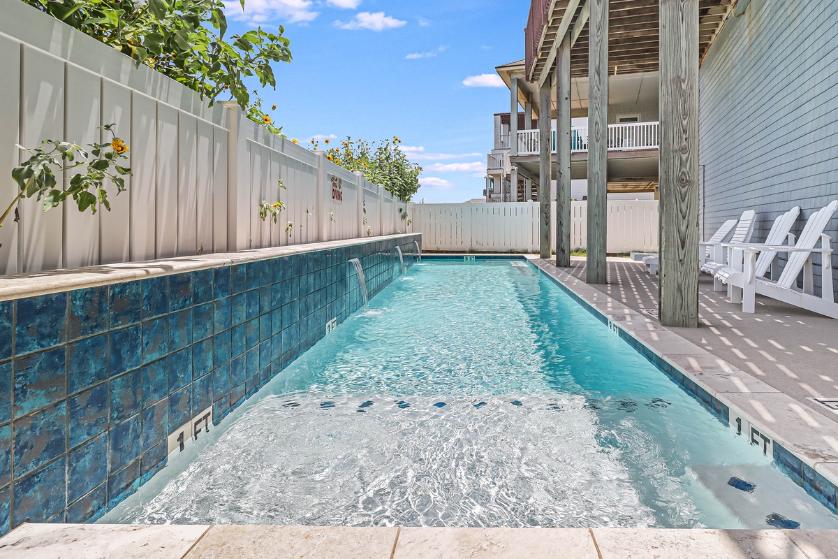Dive into your private oasis! Sparkling blue waters await surrounded by comfortable loungers and lush greenery for perfect poolside relaxation.