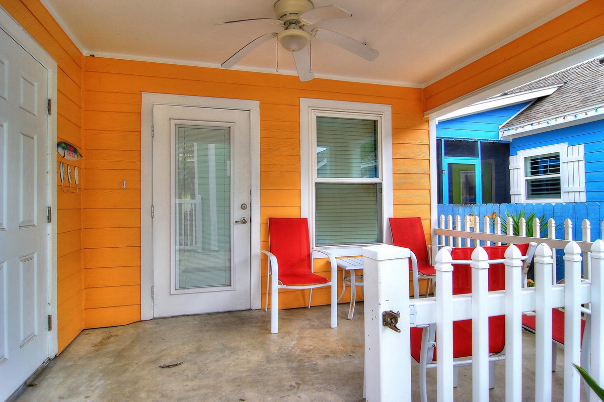Your bright orange porch welcomes you with vibrant red chairs and a white table—perfect for morning coffee or sunset conversations in this cheerful space.