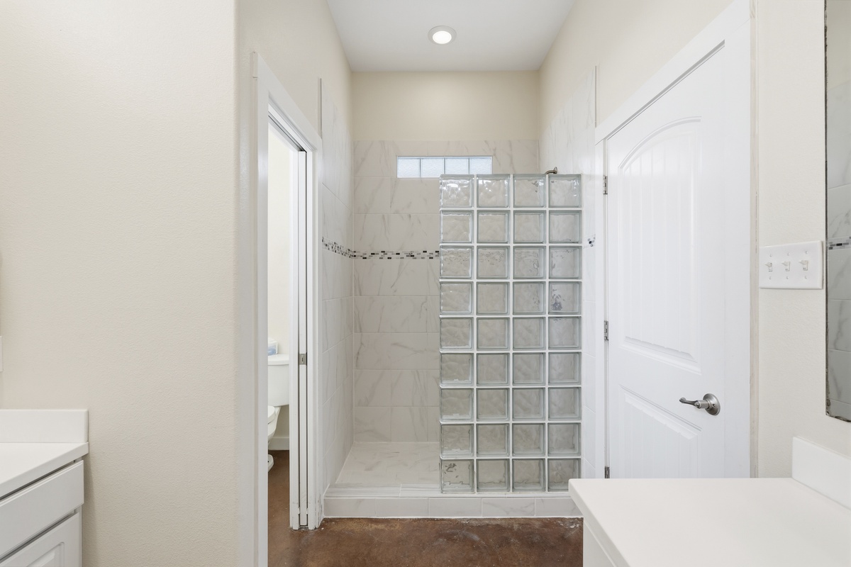 Refresh yourself in your private walk-in shower with glass block wall, elegant marble-look tile, and decorative accent strip welcoming you after a day of adventure.