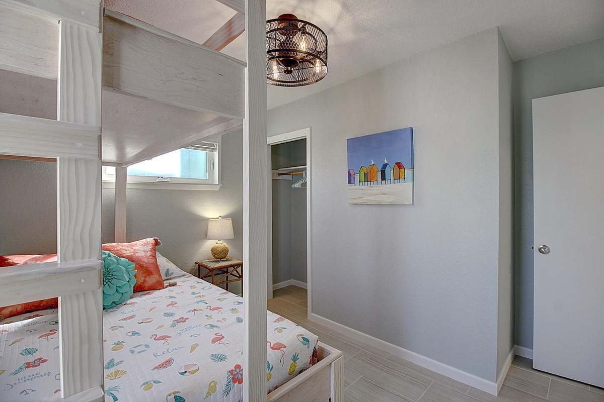 Your kids will love this cheerful bunk room with colorful bedding and coastal artwork, perfect for seaside dreams.