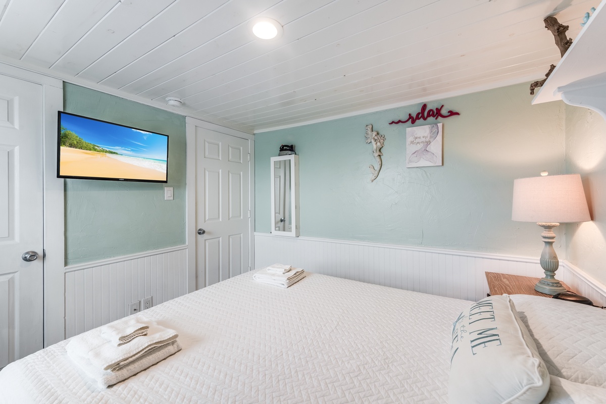 Drift off in this serene bedroom with coastal vibes, soft mint walls, and beach scenes on your wall-mounted TV.