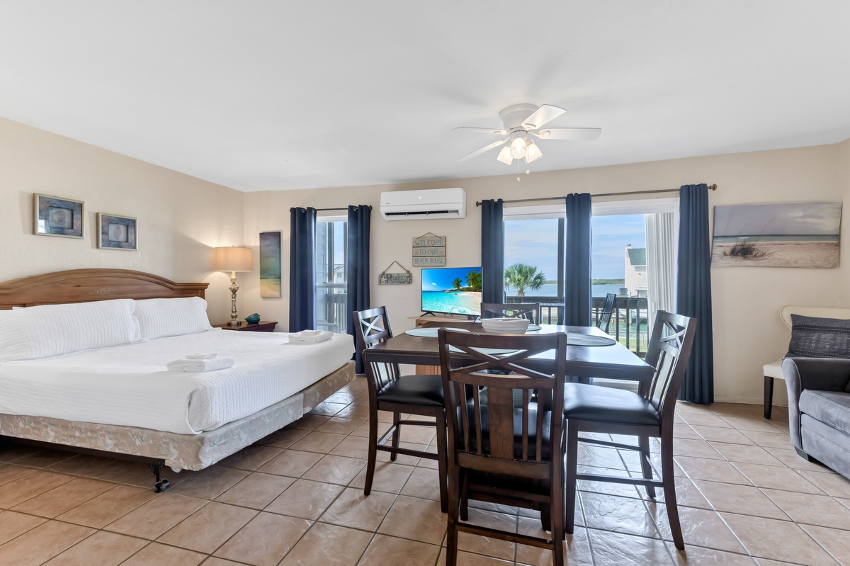 Your spacious oceanfront suite blends comfort with stunning sea views, featuring a cozy bed, dining area, and balcony access for perfect relaxation.