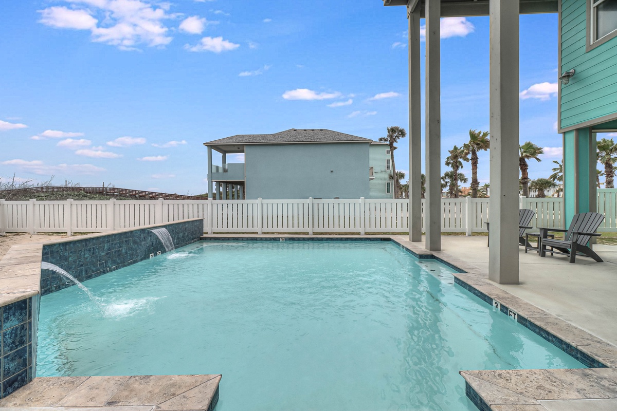 Dive into your private pool with soothing waterfall feature, surrounded by coastal charm and swaying palms.