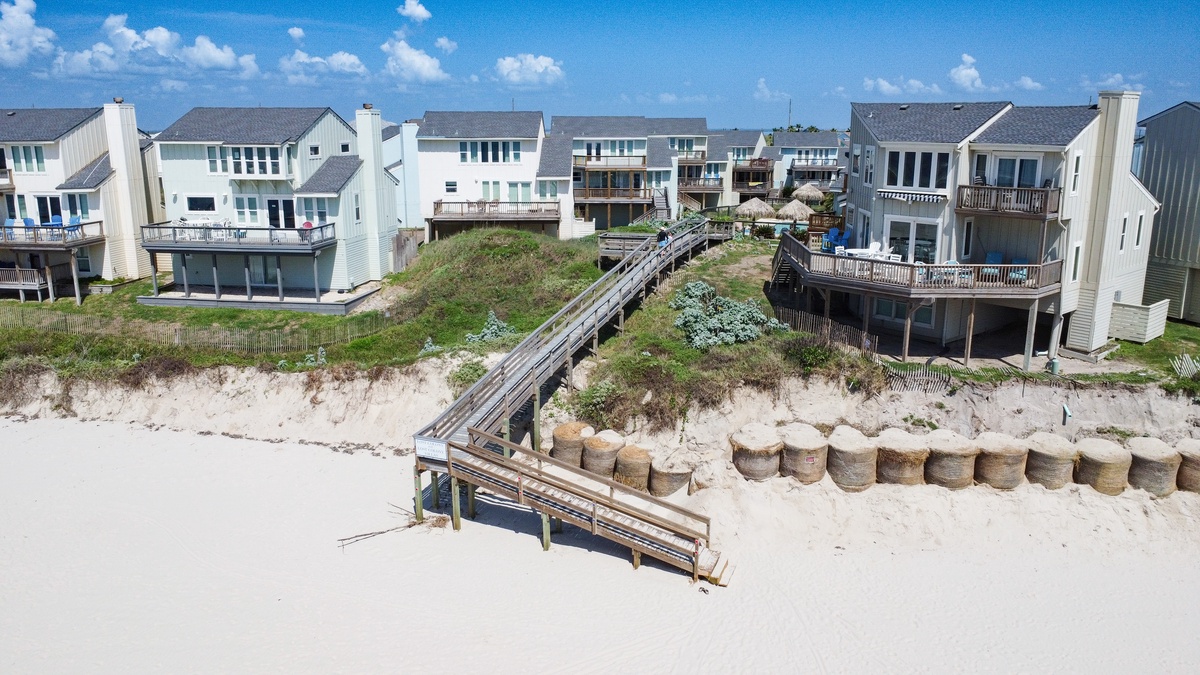 Oceanfront homes line pristine beach with private walkway access to sandy shores.