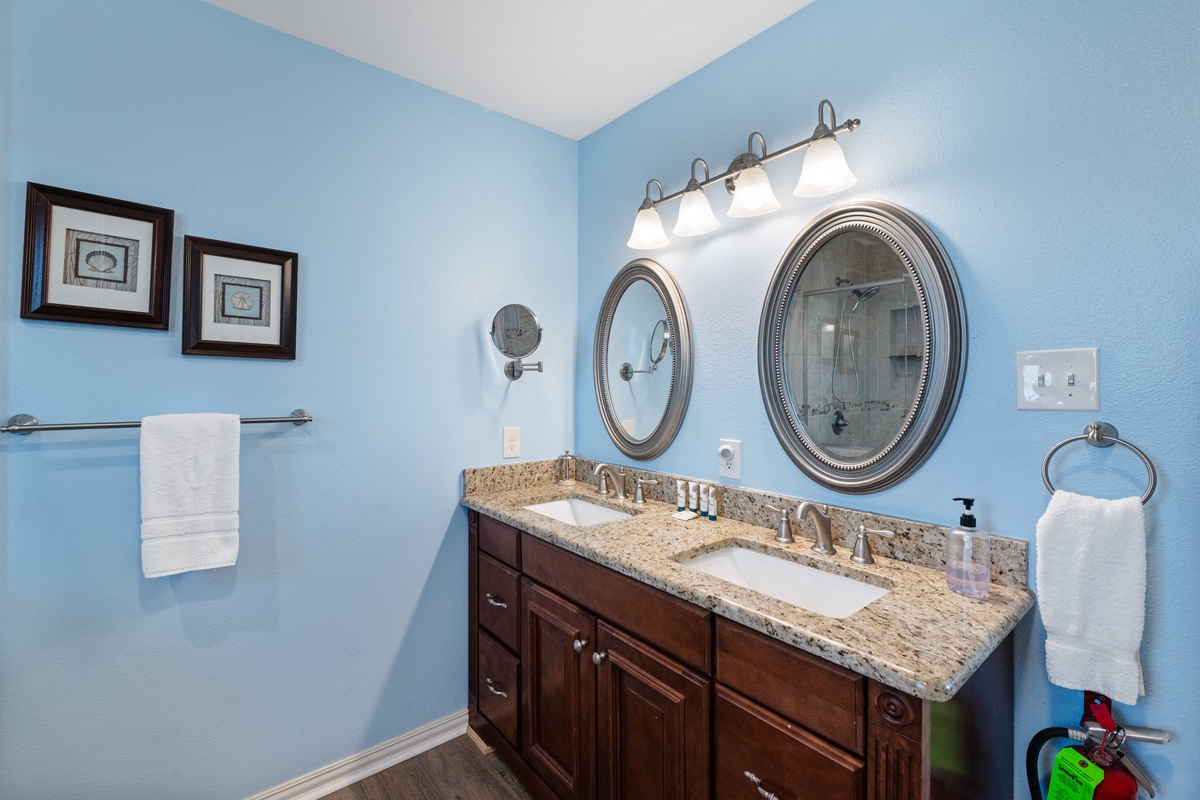 Your elegant bathroom features dual sinks with granite countertops, perfect lighting, and soothing blue walls for your morning routine.