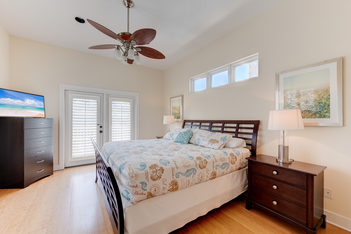 Drift into peaceful sleep in this serene bedroom with coastal bedding, warm wood furnishings, and your own French door access to outdoor space.