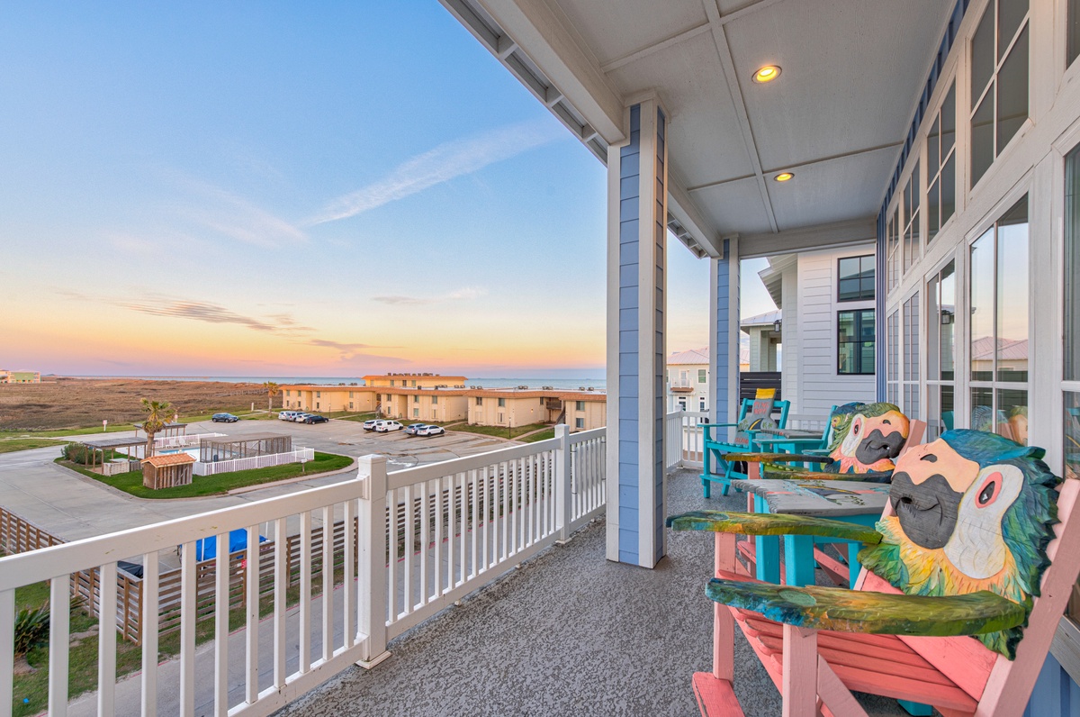 Colorful parrot-themed chairs await on this spacious balcony, where you'll watch stunning sunsets over the coastal landscape.