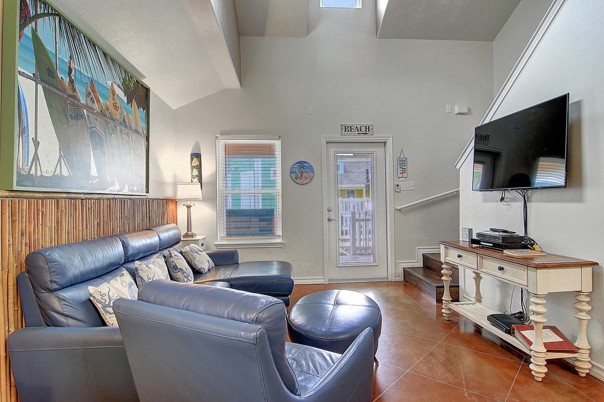 Unwind on the plush blue leather sectional while enjoying tropical-themed decor and entertainment on the wall-mounted TV.