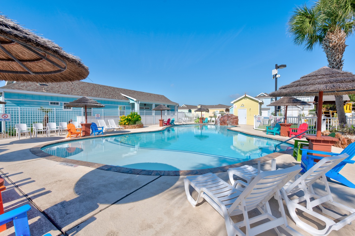 Dive into crystal-clear waters surrounded by tropical palms and colorful loungers—your perfect poolside paradise awaits.