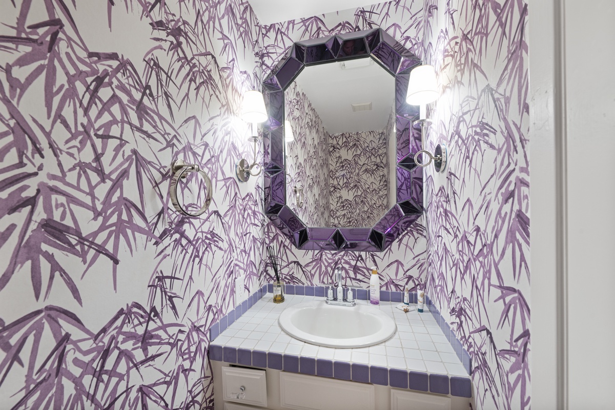 Step into your private powder room adorned with stunning purple botanical wallpaper and elegant sconce lighting for a luxurious touch.