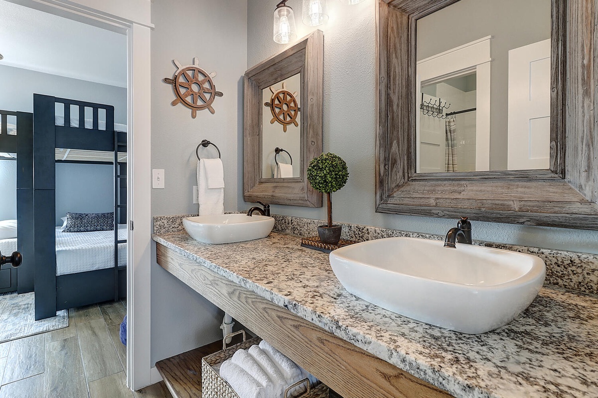 Unwind in your elegantly styled bathroom with dual vessel sinks, rustic wood accents, and nautical touches that create a coastal retreat vibe.