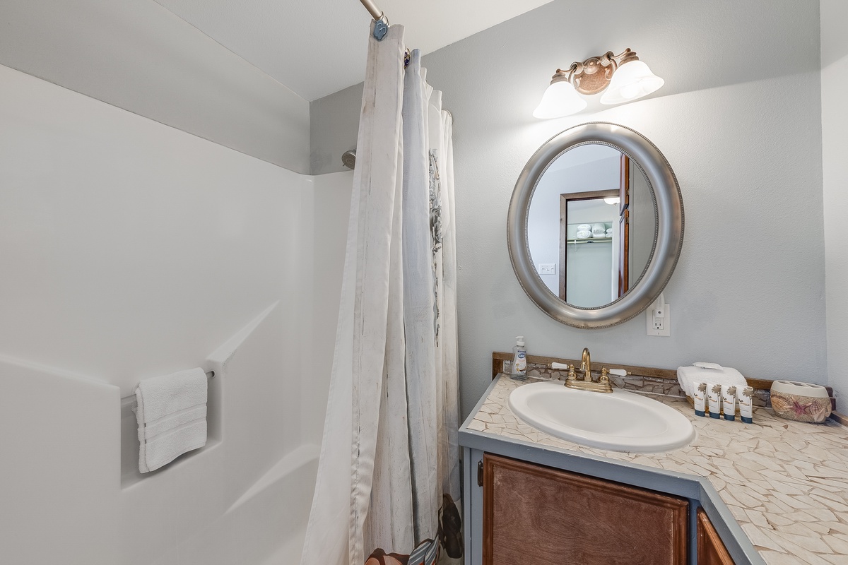 Refresh in your private bathroom featuring elegant marble countertops, soft lighting, and a spacious shower-tub combo for ultimate relaxation.