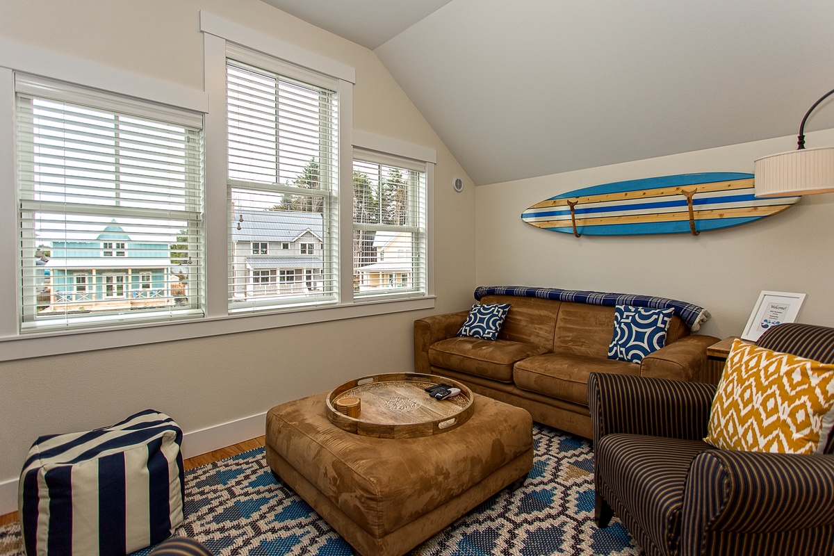 Second floor media room complete with a comfy sofa, arm chairs, and ottoman.