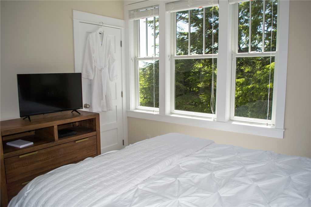 Second floor primary bedroom with flat screen TV and view of the woods