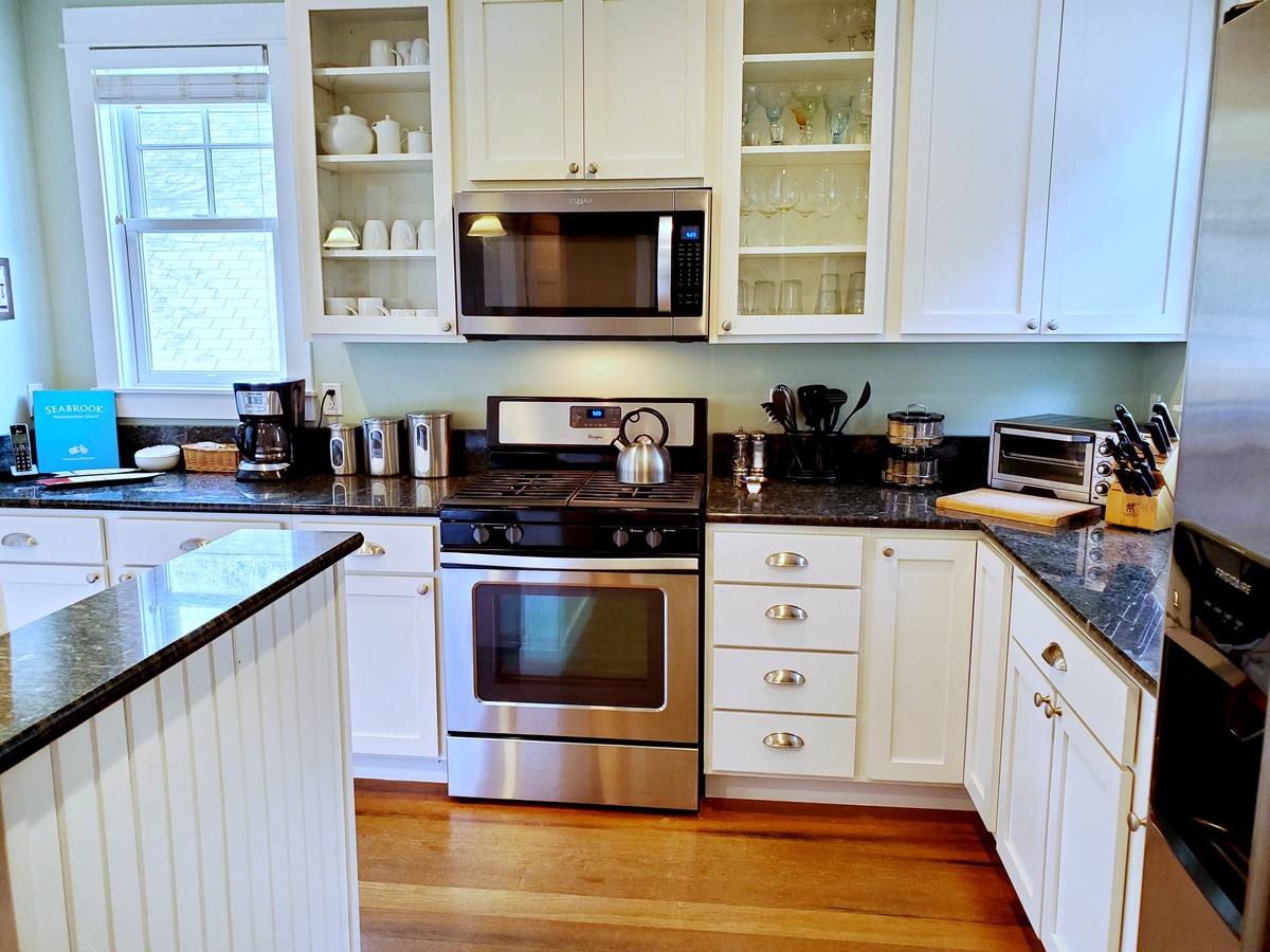 Fully-equipped kitchen boasts stainless steel appliances, granite countertops and bar seating