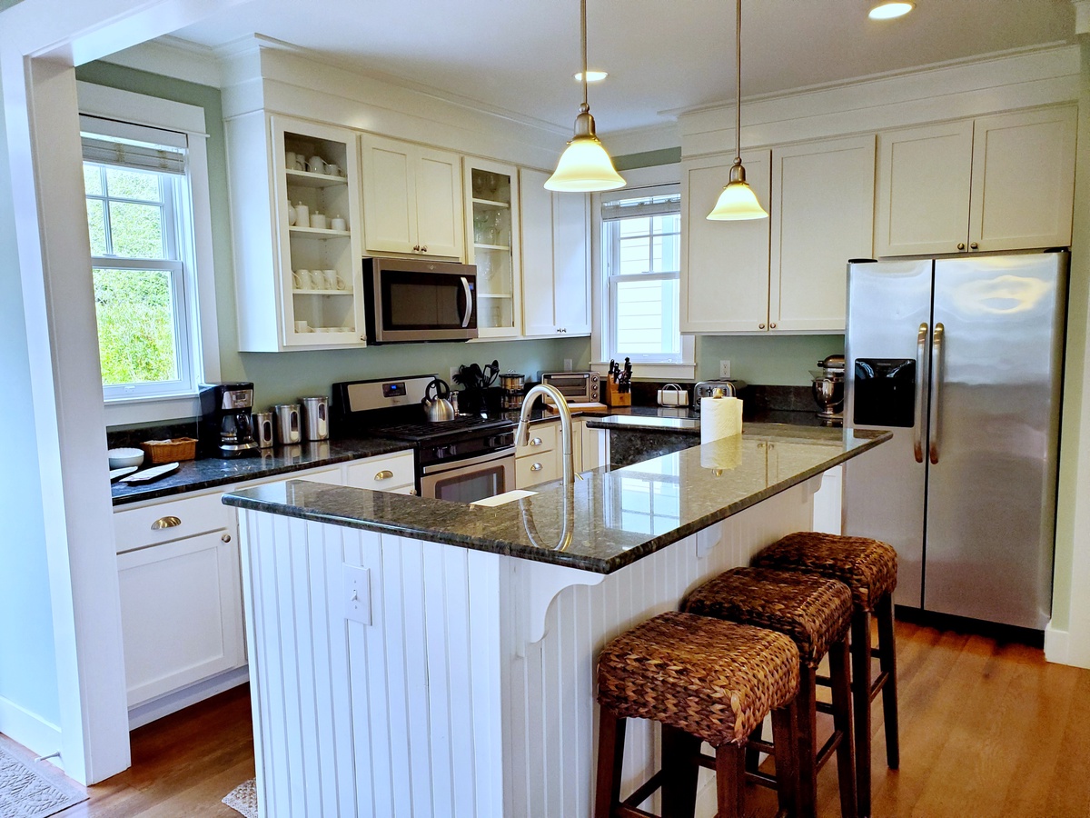 Fully-equipped kitchen boasts stainless steel appliances, granite countertops and bar seating