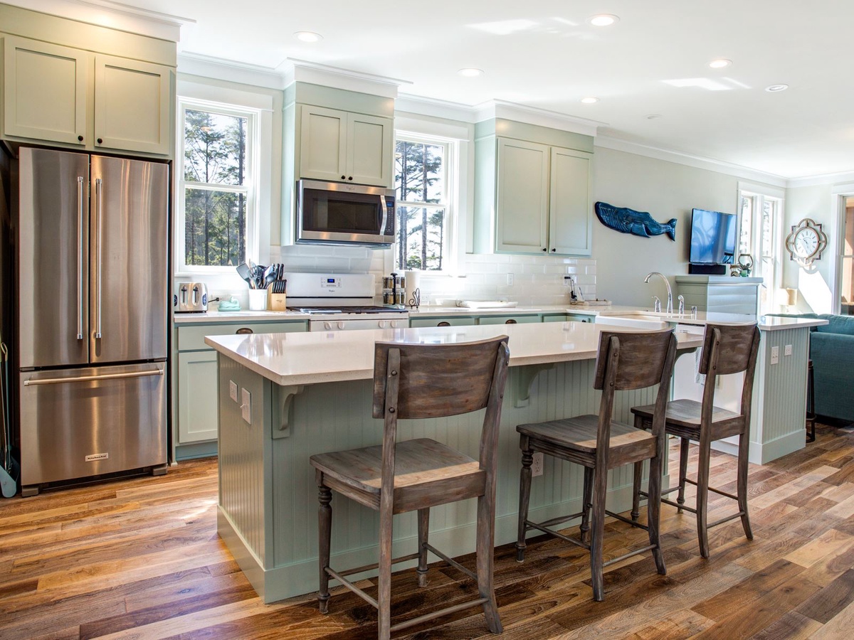 Kitchen with high end appliances, gas stove, and kitchen island bar seating for three