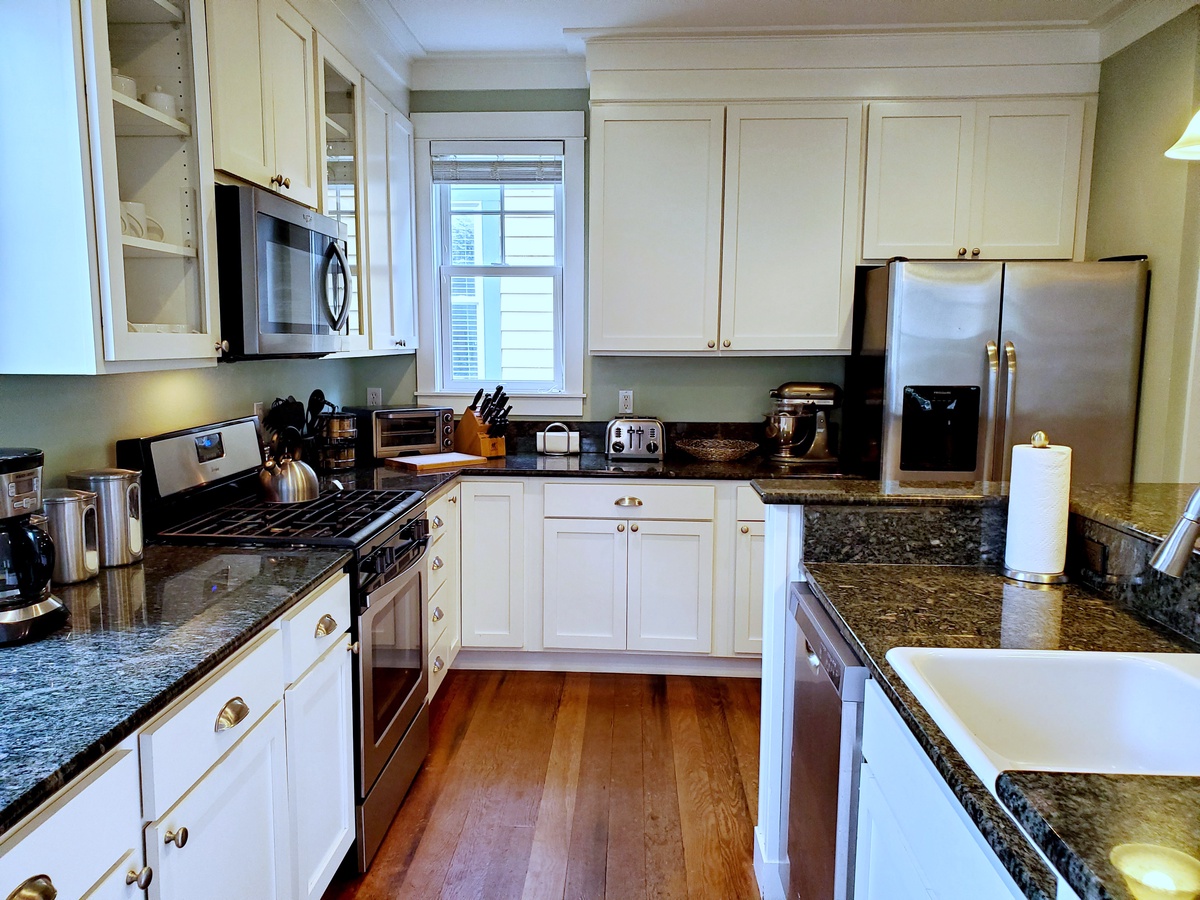 Fully-equipped kitchen boasts stainless steel appliances, granite countertops and bar seating