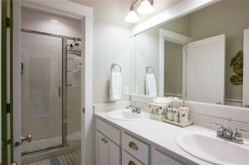 Second floor shared bathroom with dual sinks and secluded glass shower