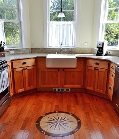 Bay-shaped, bright kitchen has lots of granite counters, a farm sink, and gas appliances