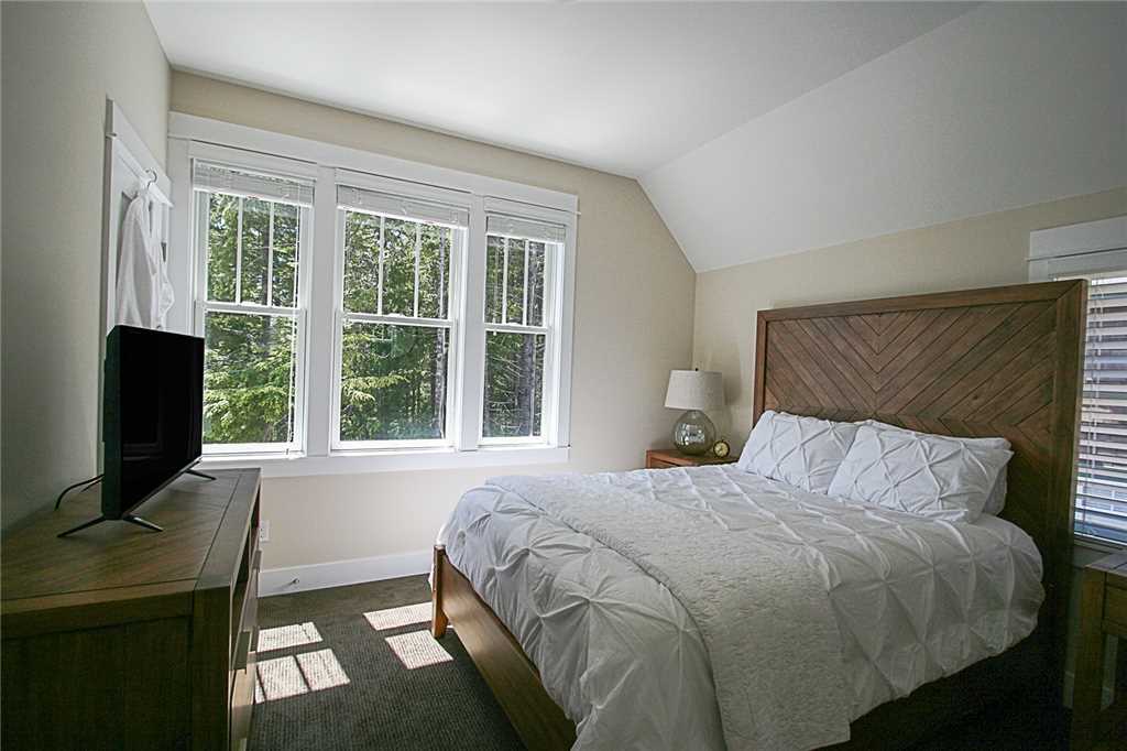 Second floor primary bedroom with flat screen TV and view of the woods